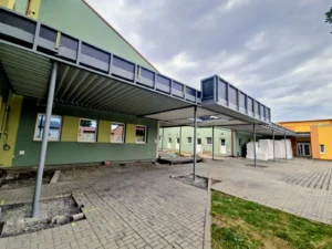 Přístavba základní školy se zastřešeným venkovním prostorem během dokončovacích prací.