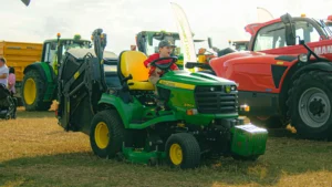dítě v traktoru na poli, traktor je zelený, dítě se směje, je krásný den