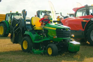 dítě v traktoru na poli, traktor je zelený, dítě se směje, je krásný den
