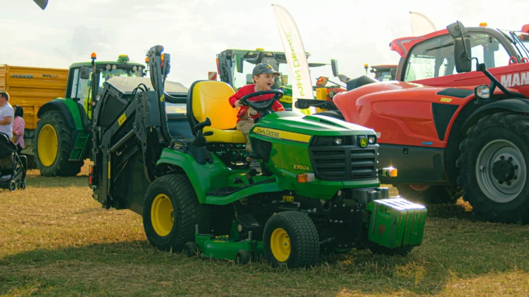 dítě v traktoru na poli, traktor je zelený, dítě se směje, je krásný den